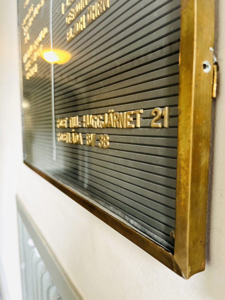 Namntavla i mässing i trapphuset på Lorensbergsgatan 3 med texten Brf Huggjärnet 21.