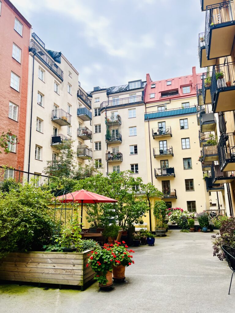 Innergård till Brf Huggjärnet 21 med grönska, balkonger och uteplatser.